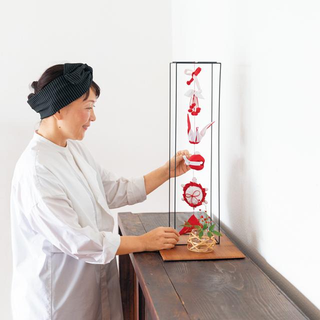 画像: 赤と白のリネンでつくられたお正月の吊るし飾り。リビングに飾って、手づくりの縁起物の人形たちがゆらゆら揺れるのを楽しむ