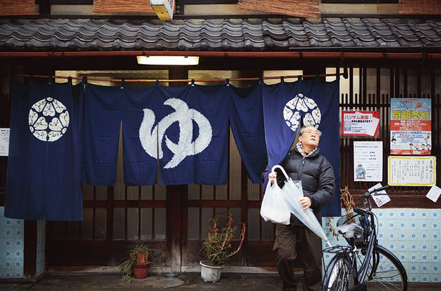 画像: 木造2階建ての「錦湯」。のれんの向こうは、右が男湯、左が女湯。今日の一番風呂は、居酒屋「てしま」の高田氣了敏さん