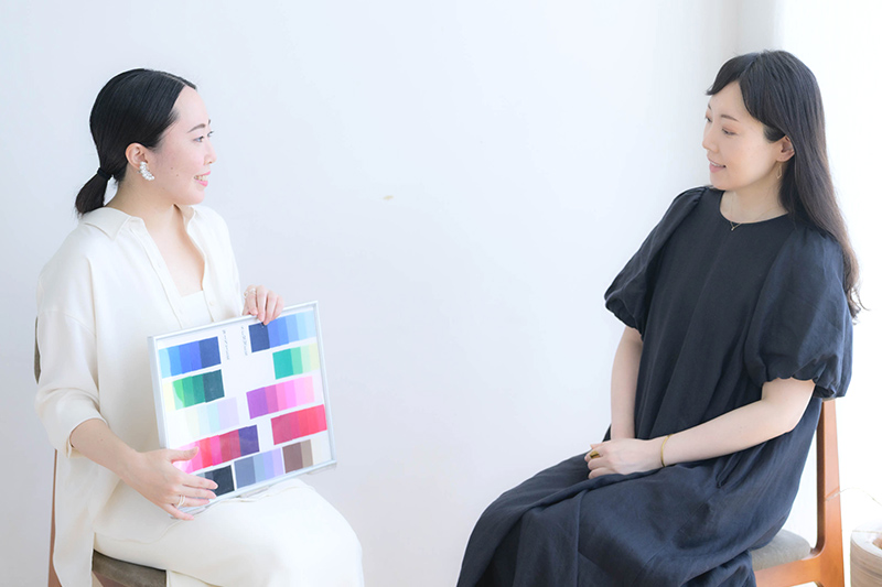 画像: 松本さんが手に持っているのはパーソナルカラーの色見本。左はウィンターで右はサマー。タイプによって似合う色が異なる