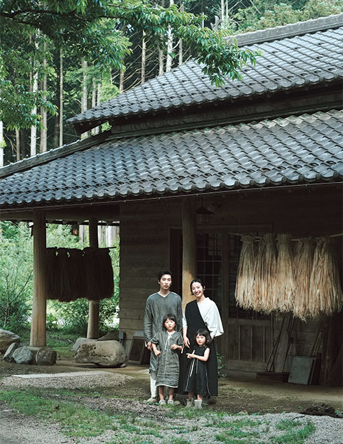 画像: 古い建物を改装したアトリエの前で微笑む、居相さん一家。大輝さんが仕立てた服が素朴な景色にしっくりとなじんでいる