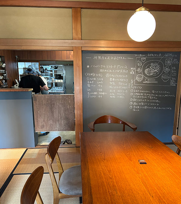 画像: 厨房横の壁一面に設置された大きな黒板には、「季節のおひるごはん」に登場するメイン料理のレシピが。以前の食堂と同様に、文字もイラストも森さんの手描き