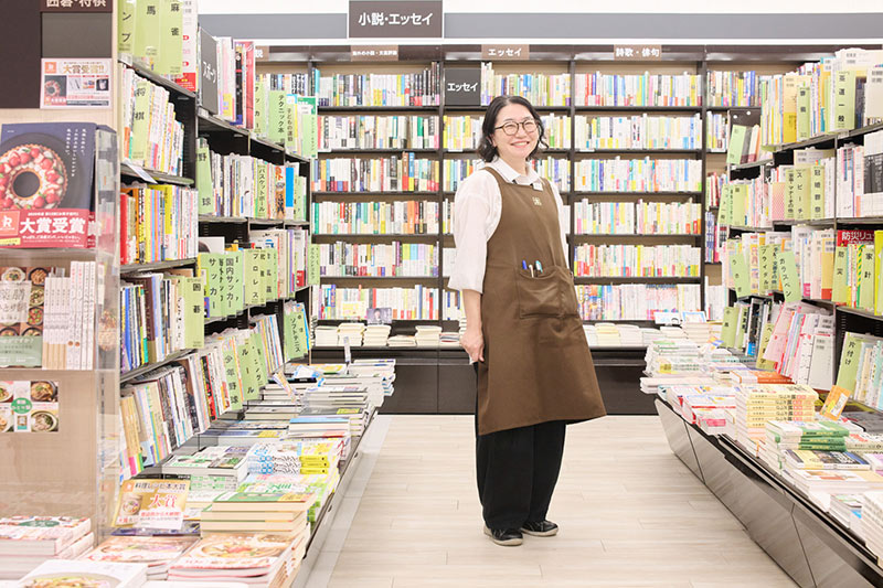 画像: 白シャツにエプロン、ポケットにはボールペンを差して。「書店員の定番スタイルです」