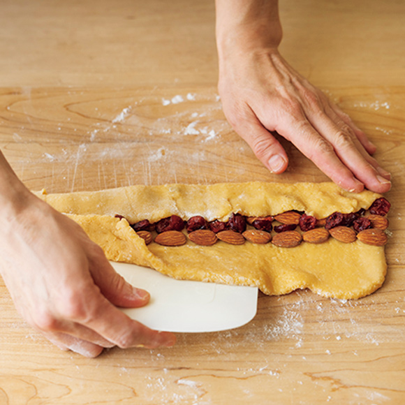 画像: まんなかに並べたアーモンドとクランベリーを覆うように、生地を三つ折りにする