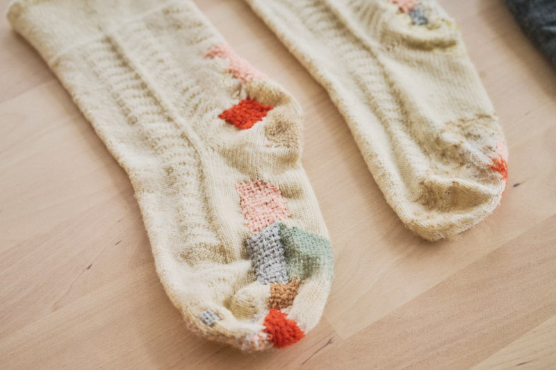 画像: 穴の空いた靴下は色とりどりの糸を使って