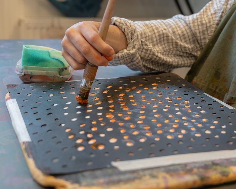画像: トントンと叩く動きが得意な利用者には、穴あきボードを手元に敷いてもらい、不規則で面白い模様を生み出していく