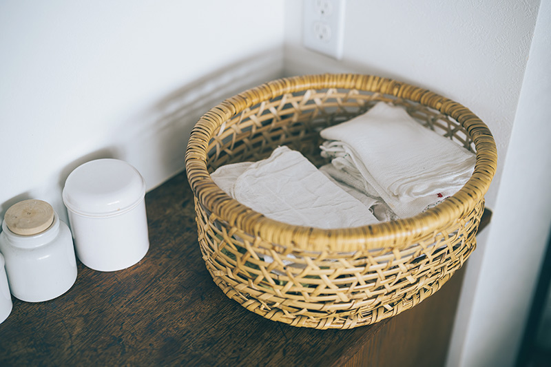 画像: 生活感が出るものは、かごに入れてすっきりと。「ふきんも大きめの竹かごにざっくり入れてオープン棚に置いています」