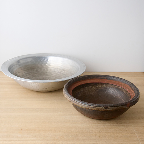 画像: アルミ鍋は直径30cmほどで4人なら十分のサイズ感。土鍋は持ち手がないタイプ。「大きめの鍋は、色や質感 ががらりと違う2種類があると、鍋のスープに合わせて使い分けられて便利ですよ」（本田さん）