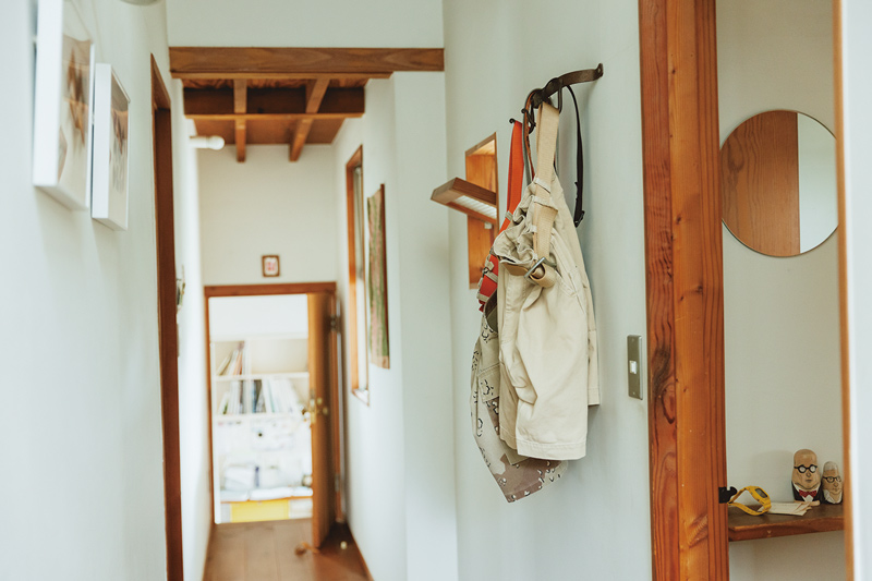 画像: 絵画やアートに混じって廊下に吊るされたハーフ丈のパンツが2本。実はこれ、夫が「次に着るもの」として事前準備で置いているのだそう