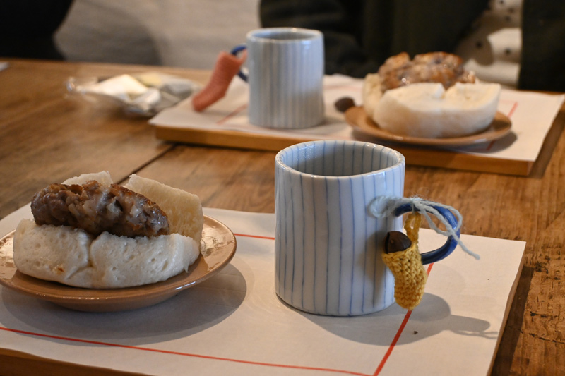 画像: 2日目は、月乃音・渡邊乃月さんによる喫茶も開催。カップにはeleven 2ndのミニソックスを添えて、桂花香鉄観音やハーブをきかせたお肉を挟んだMORIS製饅頭を味わう姿も。編み物を眺める人、手を動かす人、それぞれに会話が弾むひとときに