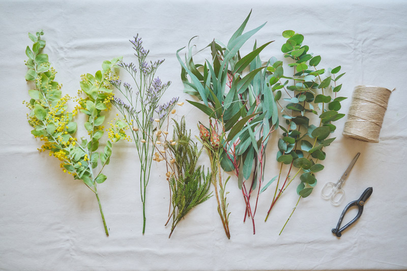 画像: 植物は、右からユーカリ・グニー2本、ユーカリ・ロングリーフ2本、リューカデンドロン（お好みで）、拾った木の枝（お好みで）、リモニウム1本、ミモザ1本。麻ひもは50cmほどに切っておく