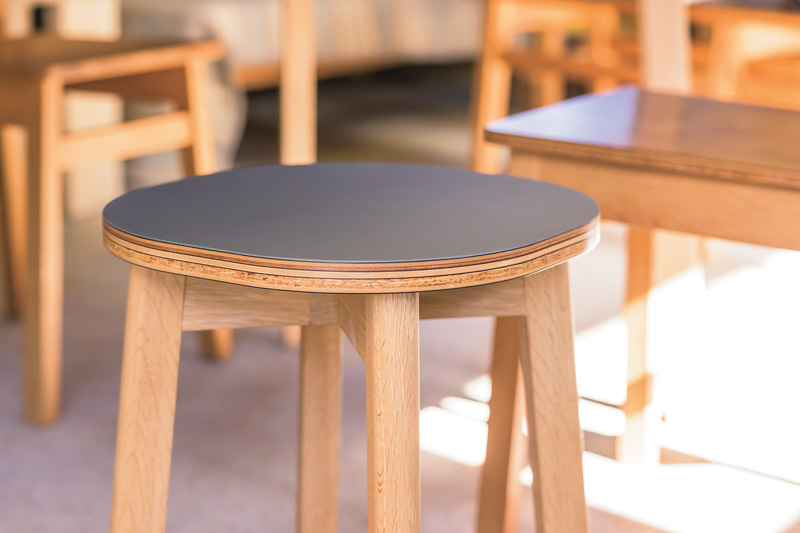 画像: 座面にオリジナルの合板を使用したスツール。スモーキーな色味の座面と、サイドから見える合板のシンプルな積層が美しい。丸みを帯びた座面や脚の角など、細部にこだわりを感じる