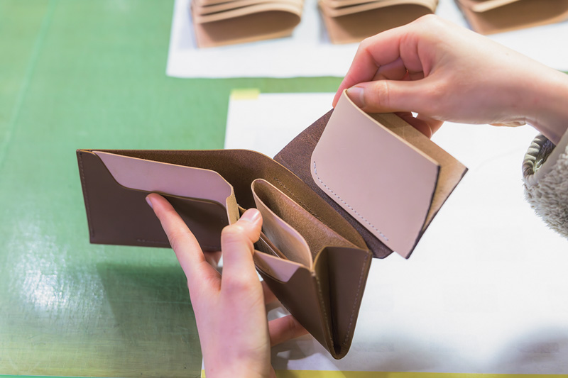 画像: 財布のパーツを見せてもらっているところ。これは小銭入れの部分。各パーツをまとめて仕上げてから、最後に組み合わせる。革に傷がつかないよう、注意を要する作業