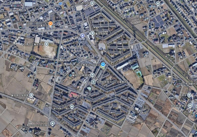 画像: 関根が幼少期を過ごした「わし宮団地」は現在も健在です。平地に「板状階段室型住宅」が建ち並んでいてその合間に公園が整備されていて住みやすそう。並行配置を大胆な幾何学型に崩していく配置プランは、埼玉県の平野部の団地らしい特徴な気がします（画像：©2026 Airbus、Maxar Technologies、地図データ：＠2026 Google）