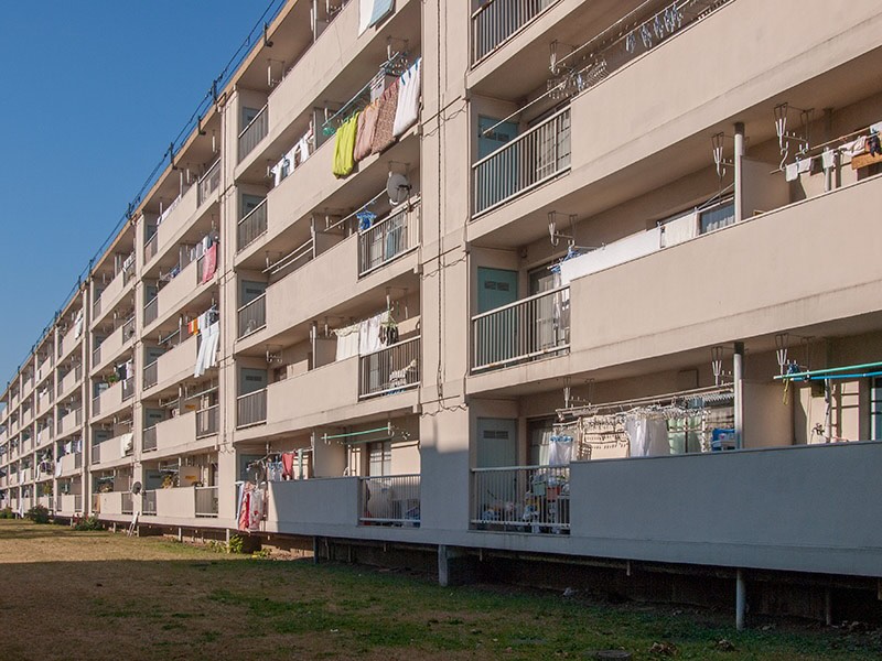 画像: たぶん40号棟居室側の写真です。ベランダに水色の扉の物置が設けられているのが面白いです。基礎から1階の床までの高さが低いので、1階に湿気の問題が出ていなかったのか心配です