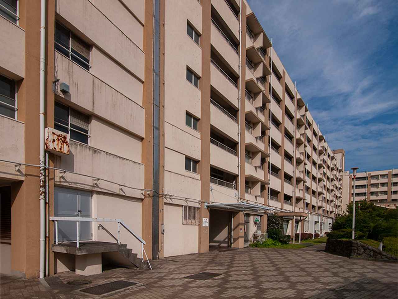 画像: 中央左側のステンレスの板が、建物のつなぎ目。手前が単身棟の53号棟、奥がファミリータイプの52号棟。52号棟の1階には郵便局がありました