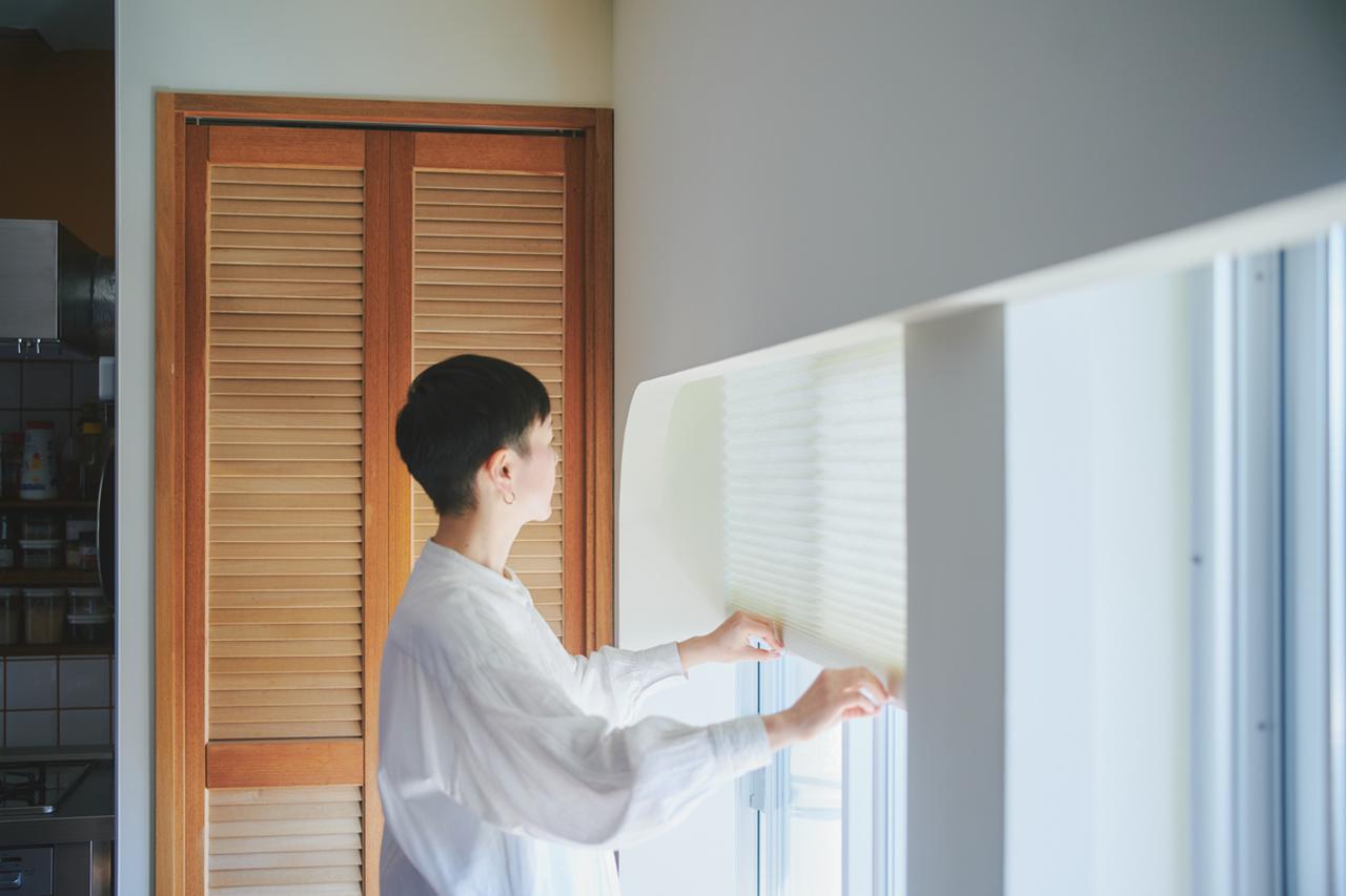 画像: 角にアールを施した壁は、新たに造作したもの。家のインテリアと調和するシェードを選んだ。サッシの上部を壁で隠せるから、窓まわりが軽やかな印象に