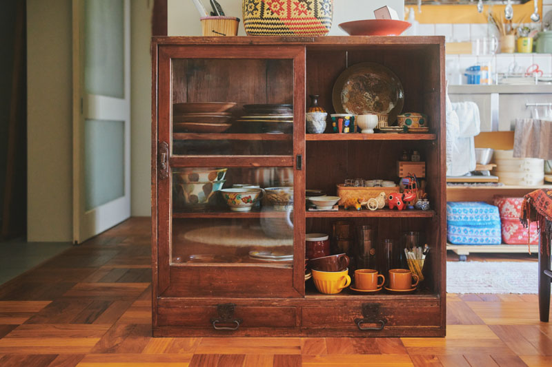 画像: 古道具屋さんで買い求めた木製ガラス戸棚。「ガラス戸で、お気に入りの食器を見せつつ収納できるのが楽しい」とタシロさん
