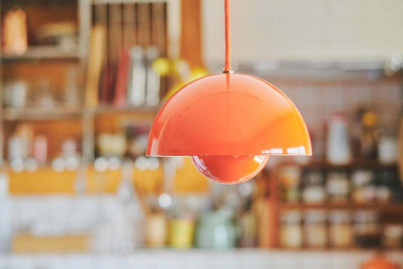 画像: ダイニングにある鮮やかなオレンジ色のペンダントライト「フラワーポット」は、北欧の名作照明。この照明を台所の主役に