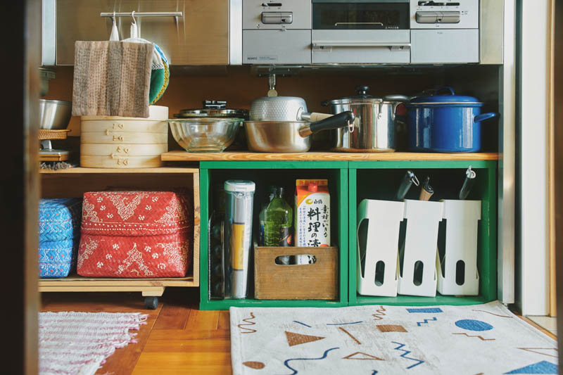 画像: キッチン台下の収納。グリーンのカラーリングが楽しい。左の棚は、キャスターをつけて引き出せるよう工夫も