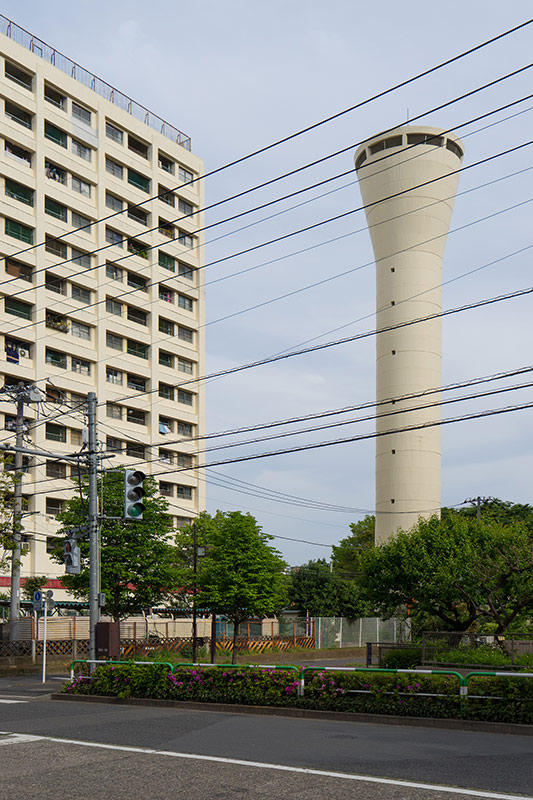画像: こちらは2017年の高層棟E-47号棟と給水塔です。給水塔は、塔の上のタンクに水をポンプで引き揚げ、そこから落ちる水の圧力で団地の建物の最上階まで水を送るという仕組み。ですから、給水塔がある団地では給水塔の頂上の標高が一番高くなるのです