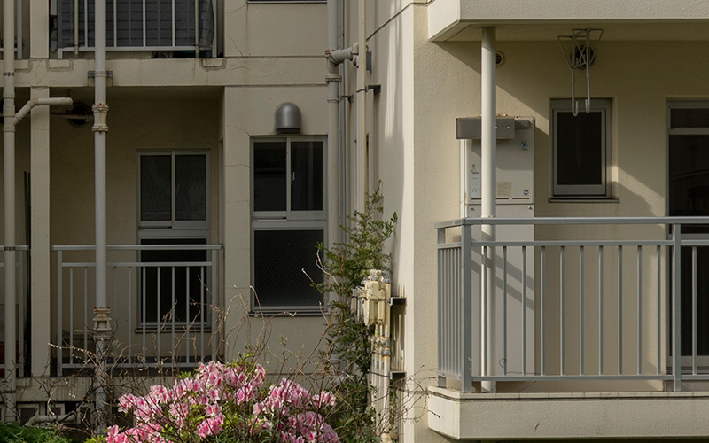 画像: 板状階段室型住宅のベランダ側も拡大して見ました。右の出っ張っている部分が増築部分です。小さな窓の左についている箱状の機械が給湯器だと思います