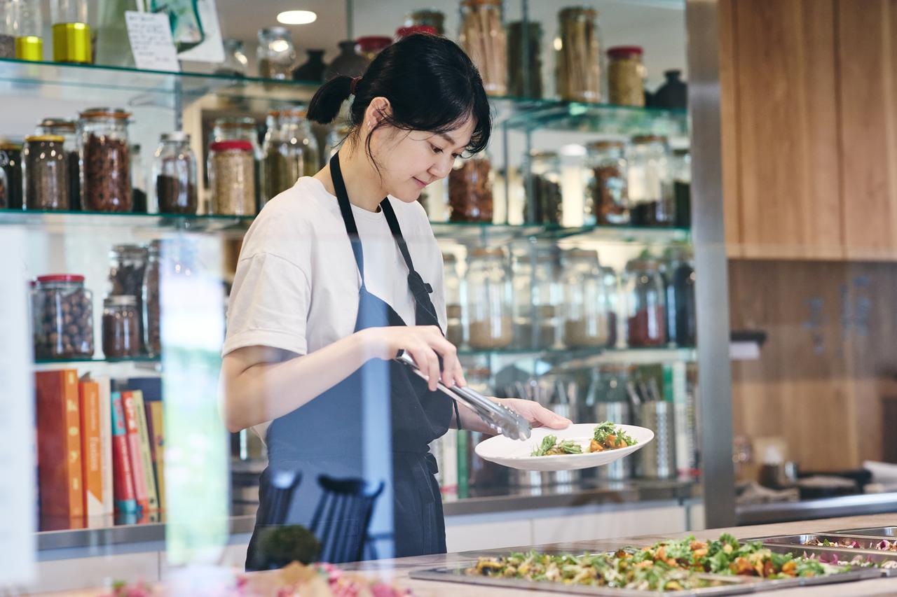 画像: 小野絢子さん。背後には世界中のスパイスや調味料がずらり