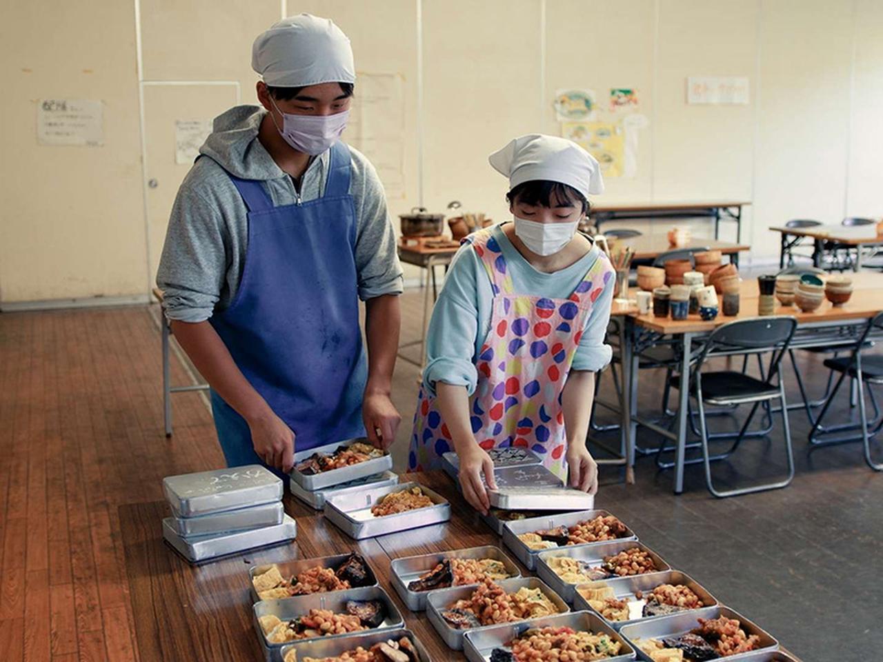 画像: 調理班がつくった昼食を2人1組でお弁当に詰めていく