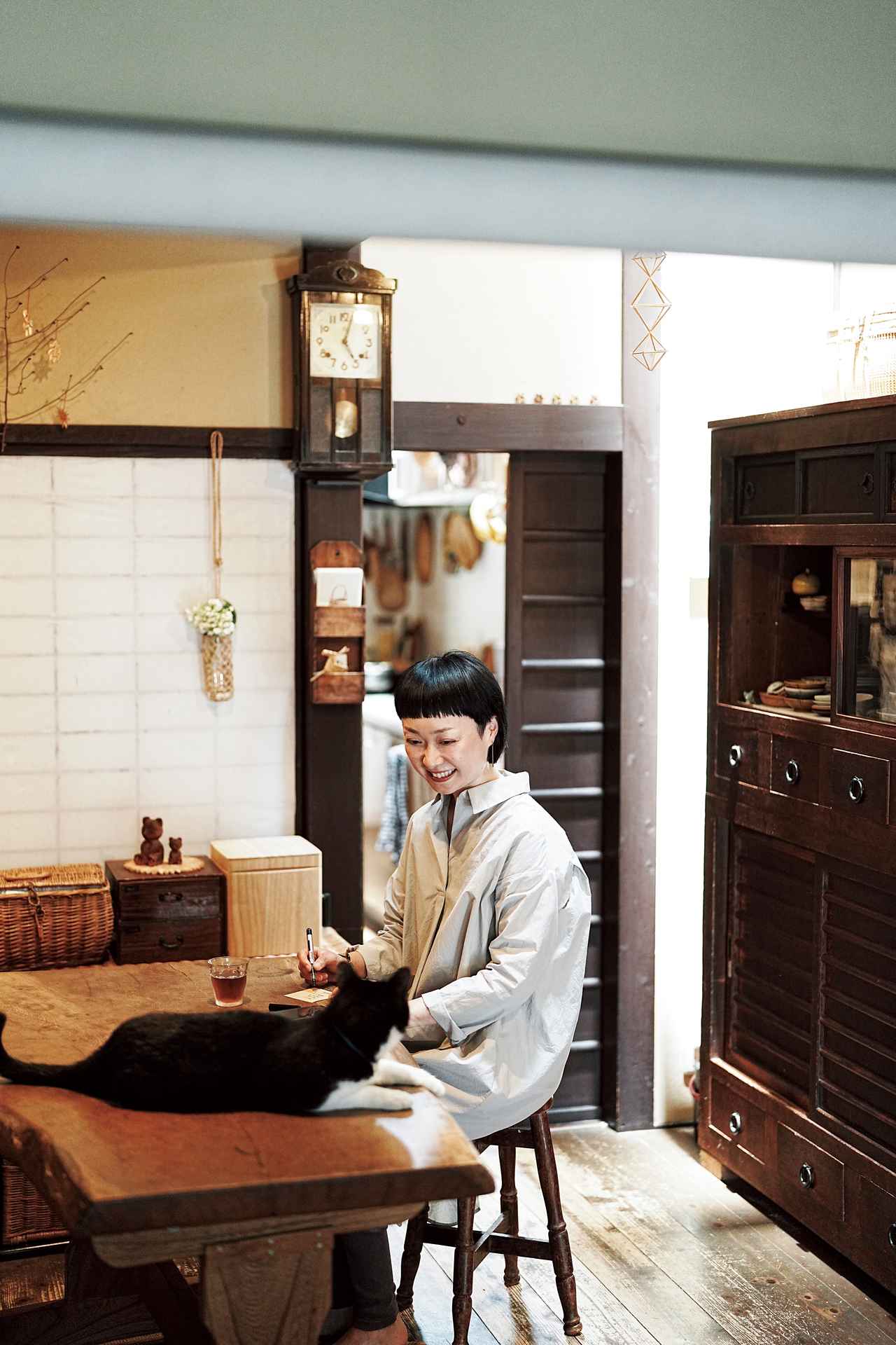 画像: 買い物前に居間でメモをとる美濃羽さん。必要なものを書くことで、買い忘れ＆買いすぎを防いで。「猫のごはんも、ちゃんとメモしました」