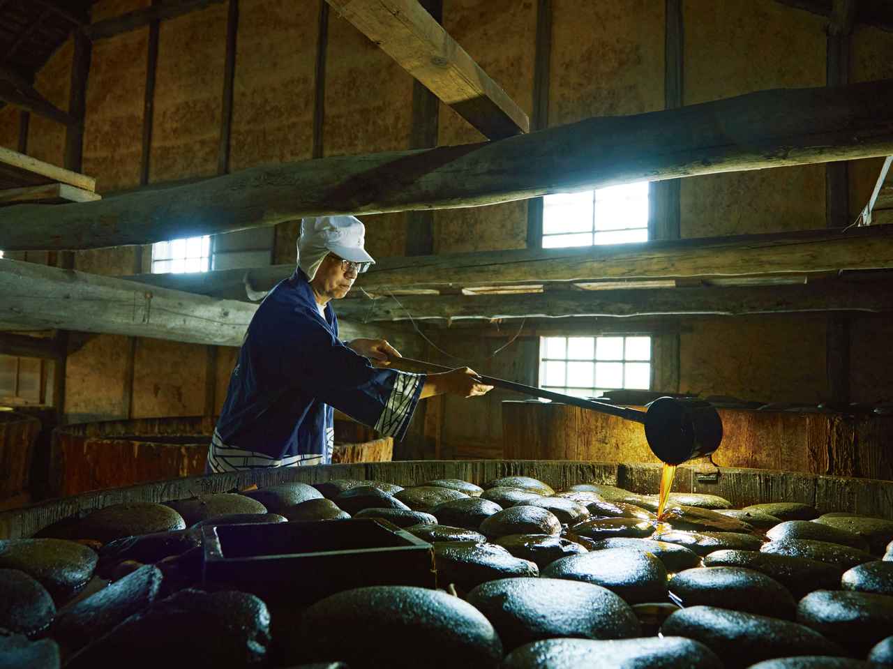 画像: 豆味噌からしみ出たたまりをかけ戻す「汲み掛け」作業。美しく並べられた重石は「長野県の木曽地方の川から明治期に運ばれてきたと聞いています」