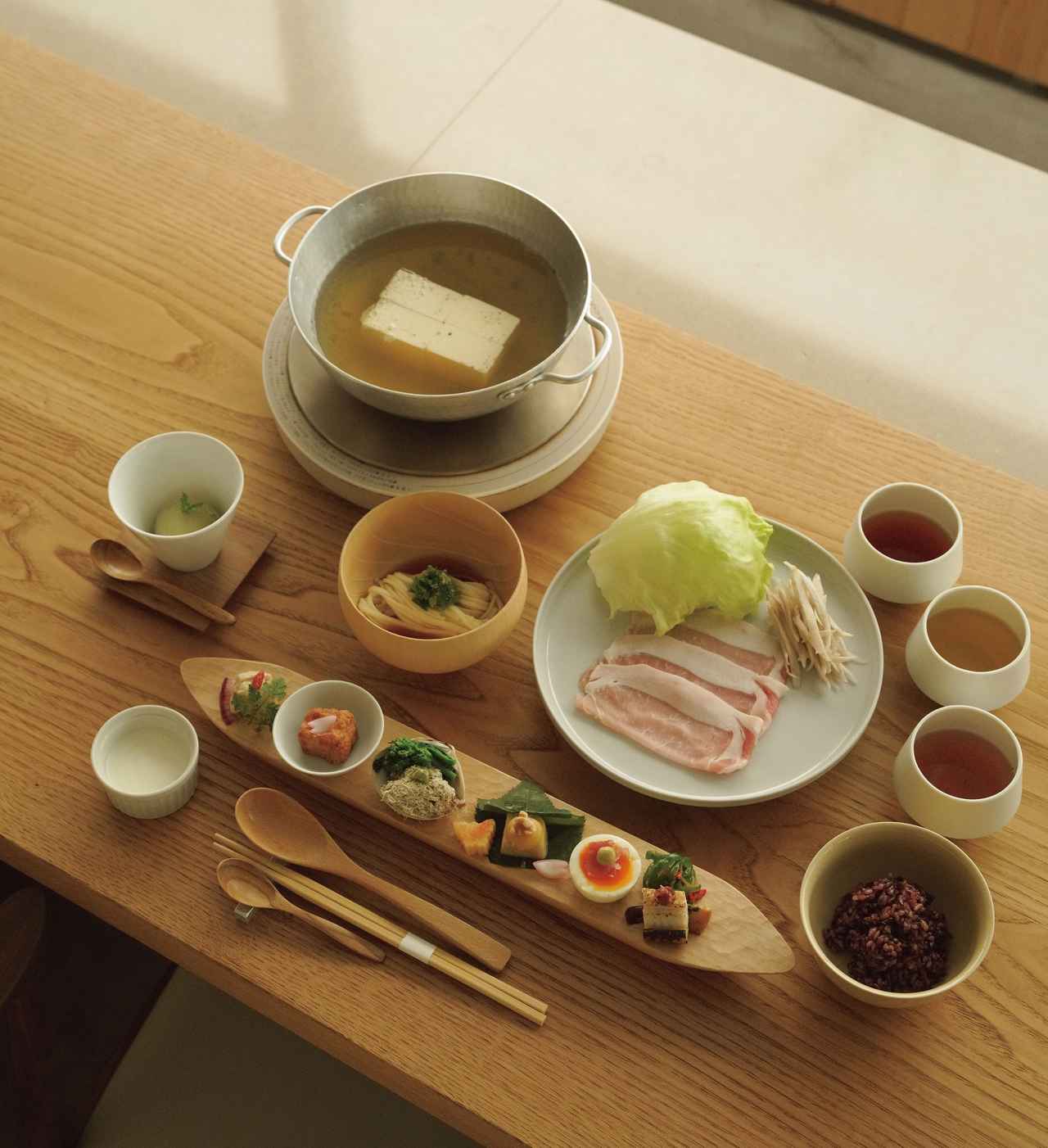 画像: 手前はごま豆腐や湯葉、季節のおばんざいが楽しめるプレート。ごはんは白米か雑穀米が選べる。くろもじなどのパウダーや、生薬塩、すだち塩で味変も可能。平日8時の回限定でコースに黄ニラ入りだし巻きをサービス