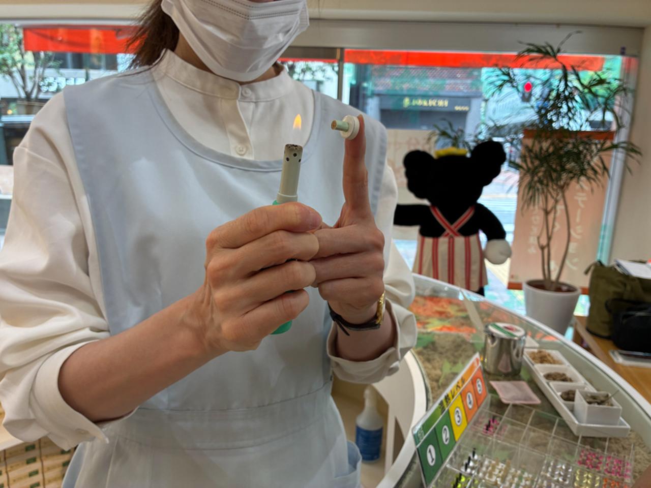 画像: お灸に火をつけるときは台座の裏のシールを剥がして指につけ、ロングライターを使います。お灸を据えたツボがほんのりと温かくなってきたら、血行がよくなってきたしるし。指先で触れてみて台座部分の熱がなくなったら、外します