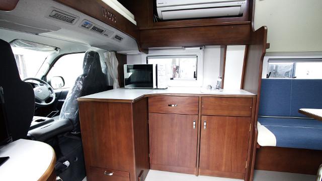 画像: 運転席後部に備えられたシンク&キャビネット。キャビネットの中には40ℓの冷蔵庫を装備。また冷暖房エアコンも標準装備となっている。