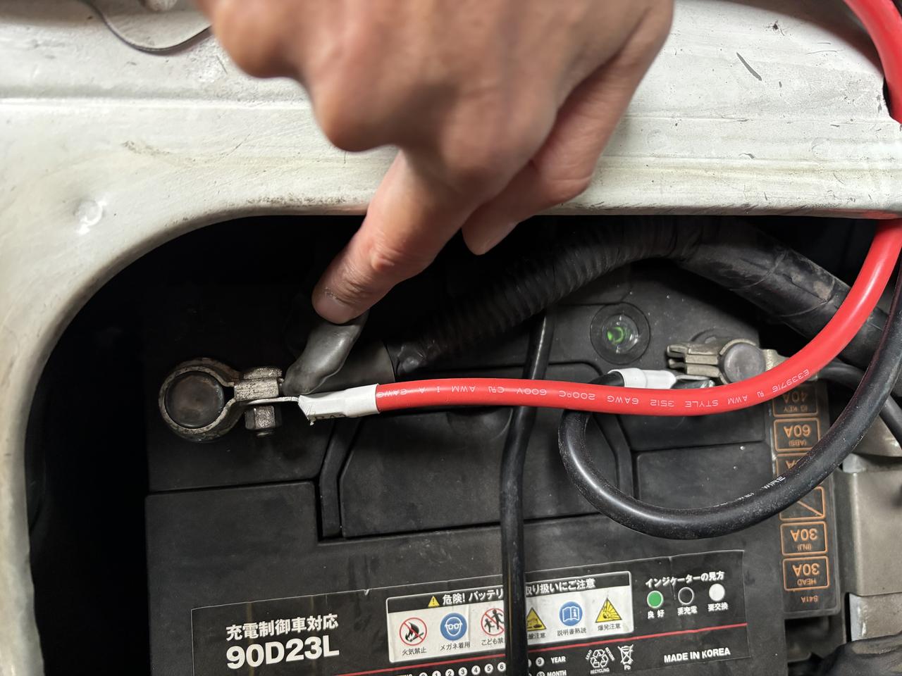 画像: 車載のメインバッテリーの端子にケーブルを装着。三菱・デリカ カーゴは、運転席の下にバッテリースペースがあり、運転席のシートを跳ね上げる必要がある。とばいえ、その手間を含めても、整備に慣れている人なら、それほど時間は掛からないはず。