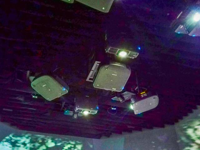画像: 天井には多くのプロジェクターが設置される。複数の種類の製品が、あらゆる角度に投写できるように置かれていることがわかるだろうか