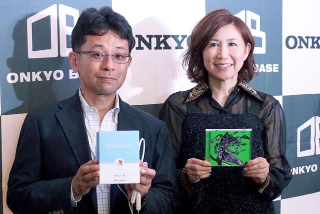 画像: 高橋さんが手にしているのは6月20日に発売されたシングル「残酷な天使のテーゼ/魂のルフラン」。意外にも、この2曲が同時の収められたシングルが発売されるのは初だそうだ。左は、プレゼンテーションを行なったオンキヨーの執行役員、奥村暢章氏 amzn.to