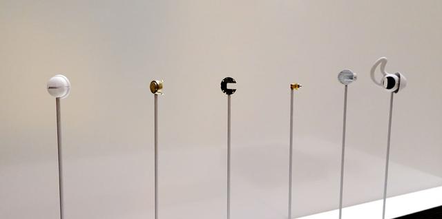 画像: ▲縁日のチョコバナナみたくなっているが、これは製品の分解模型。左から、ハウジング、バッテリー、基板、トランスデューサー、ハウジング(内部にアンテナ装着)、イヤーチップ