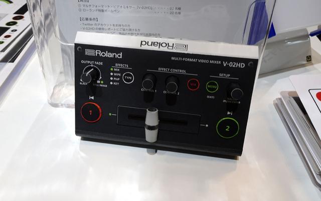 画像: ローランドブースの受付で配布されている「V-02HD」のペーパークラフト。上手に作ると、ホンモノが当たるチャンスも!