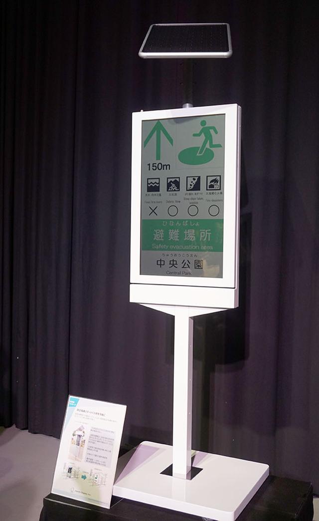 画像: スマートバス停のサンプル。液晶部分には時刻表や路線図を表示可能。必要に応じて多言語での説明等も準備できるそうだ。データの切り替えは無線経由で行なう。電力はバス停上部の太陽電池でまかなえる