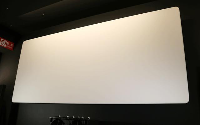 画像: スクリーンは剥き出しで設置。生地はオーエスの「サウンドマット」。サウンドホールのないタイプだが、細かく織込まれた生地を通して音が出てくる。スクリーンの後ろに、田口音響研究所の平面スピーカーが3基(LCR)設置されている