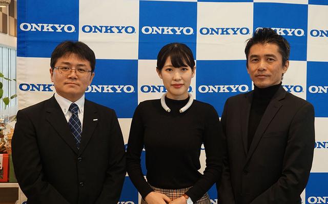 画像: オンキヨー株式会社B2B本部AI・IoT事業推進室 室長 宮崎武雄氏(右)と株式会社NTTドコモ イノベーション統括部 クラウドソリューション担当 担当課長 秋永和計氏(左)。中央はウェアラブルデバイスのデザイン担当者で、当日のデモも実演してくれた