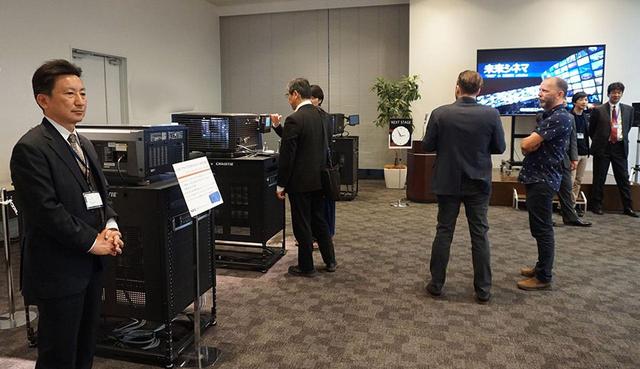 画像: 一台のサーバーからネットワーク経由で複数のプロジェクターに映画を配信する「未来シネマ」のデモ。会場では3台のプロジェクターで別々の作品を上映しており、音量調整などもアプリで操作していた。シネコンの上映環境を大きく変えそうな提案だ