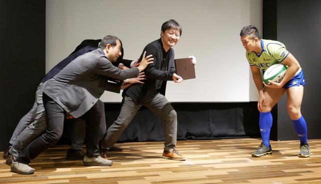 画像: 剛性感を演出するデモも行なわれた。ラグビーチーム・NECグリーンロケッツ所属の大和田立(たつる)選手が登場し、「LAVIE Pro Mobile」めがけて突進。氏の猛攻を受けても大丈夫、というもの