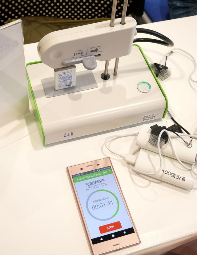 画像: こちらはイベントのために開発(製造)された簡易型のチェッカー。充電状態などは無線接続したスマホに表示される。撮影に協力してくれた方のケータイは、無事に再起動し、記録された写真を楽しんでいた