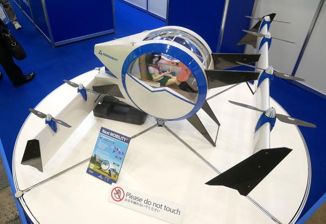 画像: ▲エアロネクストでは、次世代の有人エアモビリティとなる「Next MOBILITY」を展示。1/3サイズで、ミニチュア試作機では実際に飛行も可能。キャビンはジャイロ付きで水平を保つ機構が内蔵されている。2025年の実用化を目指すという