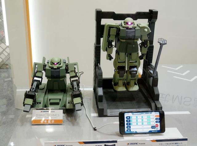 画像: ▲バンダイでは、ロボット開発会社のKONDOと提携して、自分でロボットを組み立てる「ZEONIC TECHNICS」を展開。これはパーツ状態のロボット(ザクIIね)を購入し、取説に従ってロボティスクを学びながら組み上げていくというもの。17個のモーターを制御してオリジナルのポーズ(動き=モーション)を取らせることもできるそう。そのモーションを組み合わせて、完成したロボットを操縦することも可能だ。来春発売で、価格は¥89,900+税。オプションでハンガーデッキやミニチュア作業員も用意されるそう