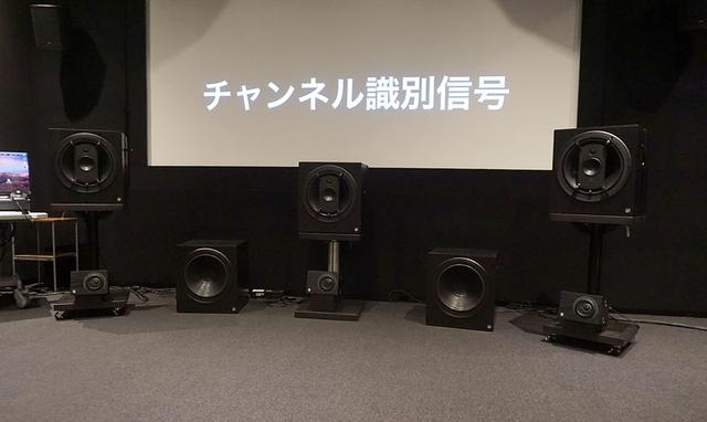 画像: スクリーンサイドのスピーカーたち。フロントL/C/Rの下に置いてあるのは22.2ch用のボトムスピーカーで、俯角15〜30度の範囲に置くように推奨されている