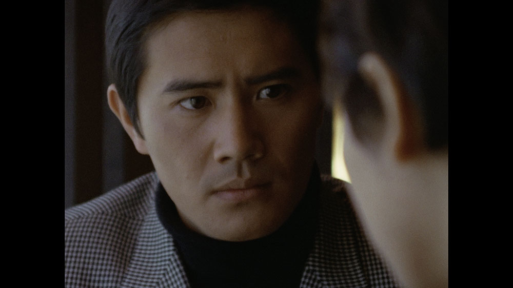 画像: 第8話「狙われた街」で、喫茶店から煙草の自動販売機を見張るダンとアンヌ。写真は4K/HDRリマスターされたもので、緊張感のあるなまなざしまできちんと再現されている