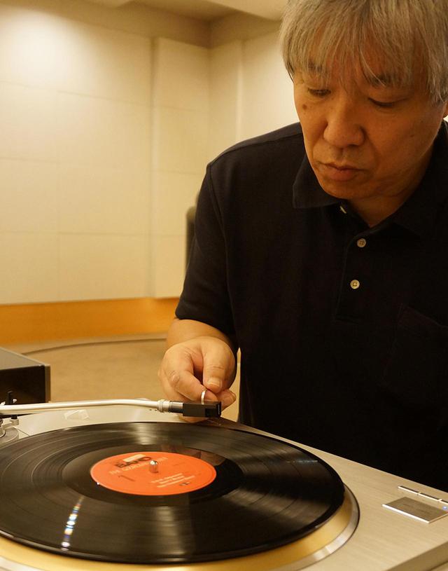 画像: ↑試聴する三浦氏。本機をアナログプレーヤーのテクニクスSL-1000Rに装着し、フォノイコライザーは出力インピーダンス10Ω以上のカートリッジに対応するフェーズメーションEA-1000を使った。