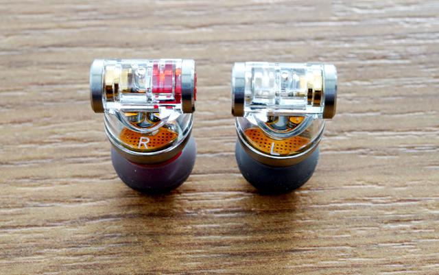 画像: イヤホン本体はT字型をしており、T字部分の両端に2種類のコネクターを装備している。本体は内部が見えるスケルトン仕様。なお、カスタム2ピンコネクターを使用時は、MMCXコネクターを塞ぐキャップも付属する