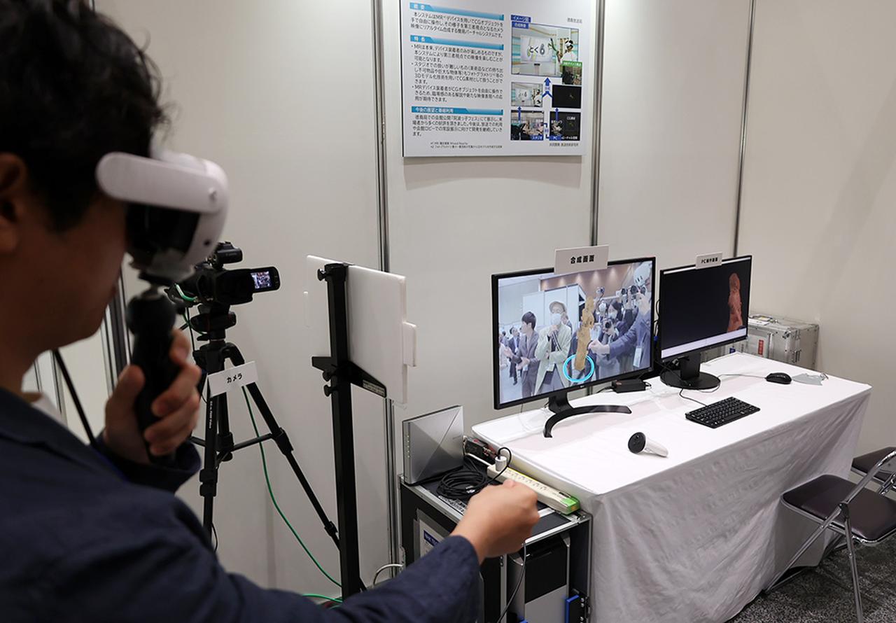 画像: MR映像には埴輪が表示されていて、MRグラス装着車はそれを手で自由に動かしていて、周囲の人はそれをモニター越しに確認できる、というもの